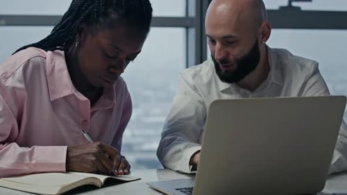 Bicultural Employees Working at Desk in Office with Panoramic Windows