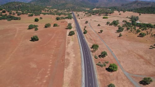 Aerial View Of Car Driving Down A Long Dirt Road In Wide Open Landscape
