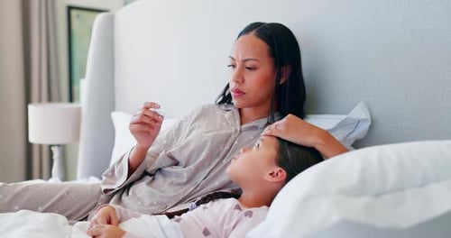 Concerned Mother Checks Child's Temperature in Bed