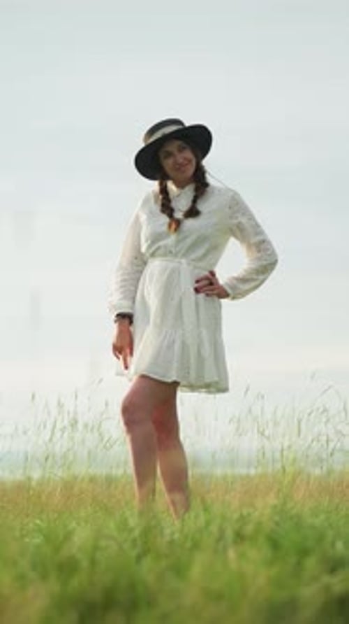 Woman Posing in White Dress As Artist Paints in Serene Grassy Field