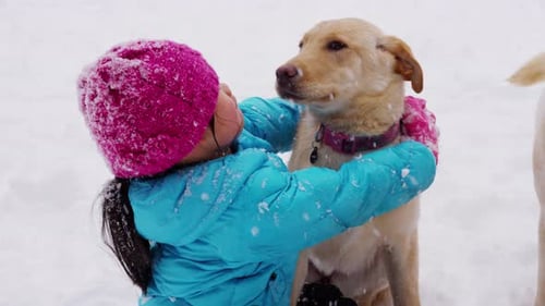 Young Girl Playing with Puppy in Snow Boy