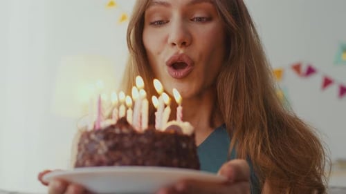 Young Woman Blows Out Birthday Cake Candles