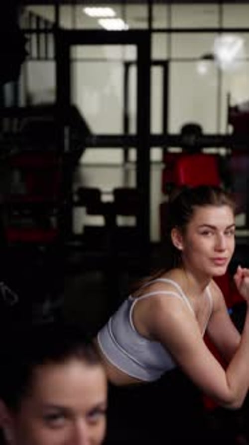 Atleta femenina concentrada en el gimnasio que se toma un descanso, mira con confianza, complexión atlética con equipo de gimnasio en el
