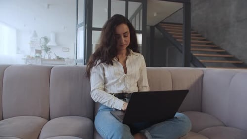 Woman Working on Laptop on Sofa at Home