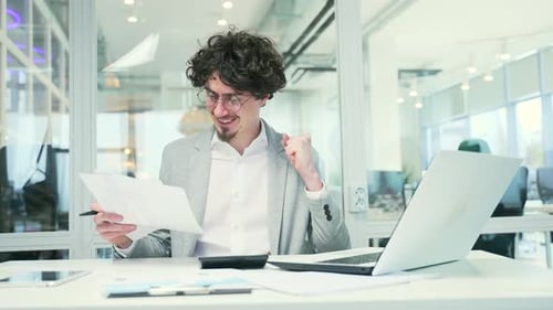 Young Professional Celebrates Success at Office Desk