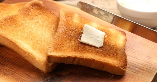 Butter Spreads on Toast on Wooden Cutting Board