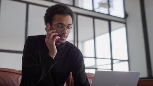 Young Adult Working at Home on Laptop, Cellphone