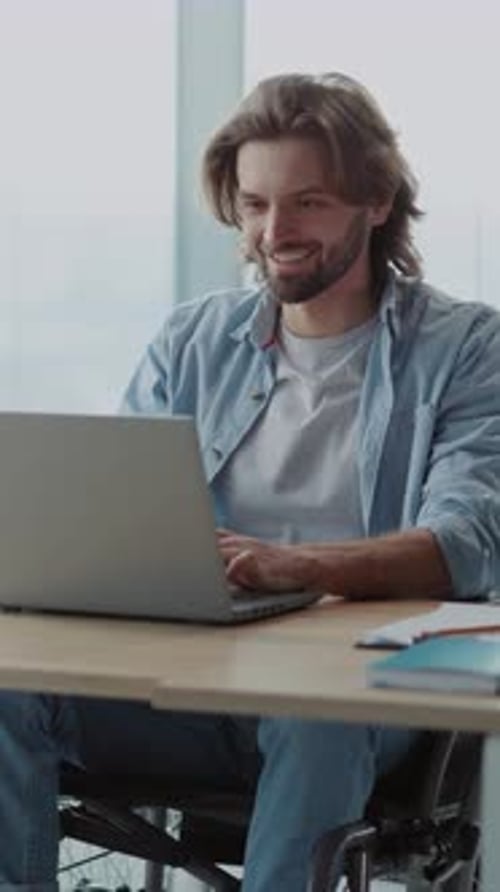 Man in Wheelchair Using Laptop in Bright Office