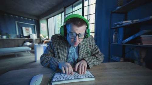 Emotionaler Typ mit Brille und Kopfhörern benutzt Computertippen auf der Tastatur Look On Screen Geek Active
