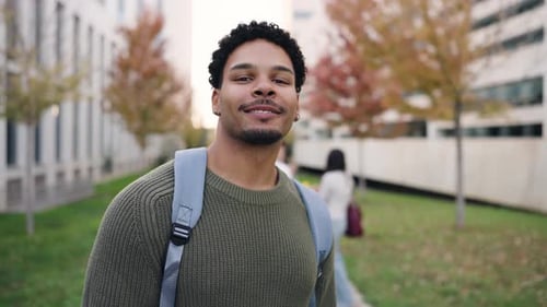 Young Smiling Student Posing at Camera on Campus