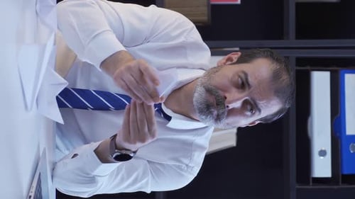 Man in Office Folding Paper Airplane at Desk