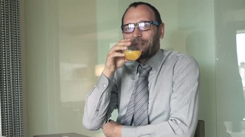 Man in Shirt Drinks Orange Juice and Smiles