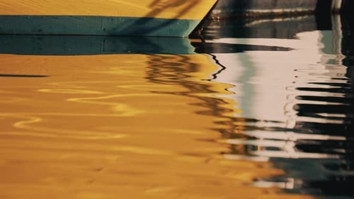 Abstrakte Nahaufnahme einer gelben Bootsreflexion auf dem Wasser