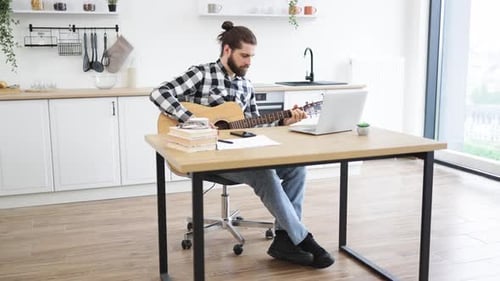 Personne caucasienne tenant un instrument à cordes tout en souriant à la webcam de l'ordinateur