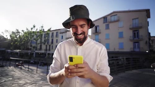Smiling Man Using Smartphone in European City
