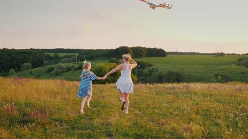 Mother and Daughter Running with Kites in Field