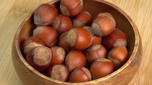 Les noisettes en coquilles tournent dans un bol en bois sur fond en bois en gros plan. Organique entier et décortiqué
