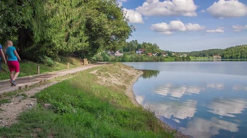 Couple takes a walk by sandy path near Smartinsko lake, Celje
