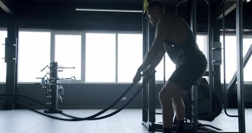 Young Athletic Man Has Workout at Gym and Exercising with Battle Rope