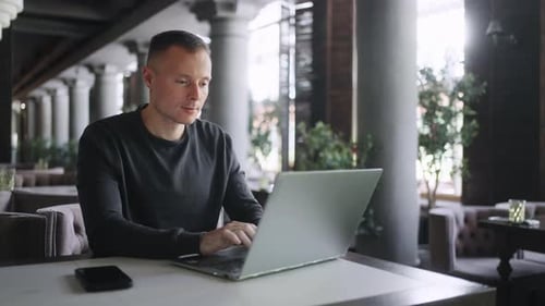 Portrait d'un homme d'affaires utilisant un ordinateur portable dans un café Freelancer avec un gadget surfant sur Internet