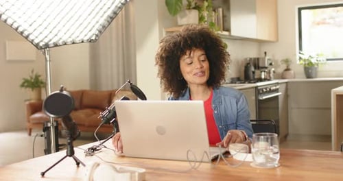 Début de la diffusion en direct, femme ajustant le micro à la lumière de la boîte à lumière à la maison, sirotant de l'eau avant de parler