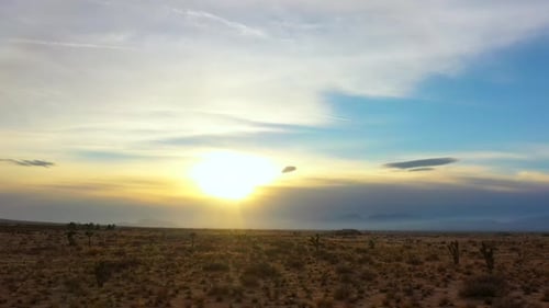Slow sliding cinematic aerial view of a sunset over the Mojave Desert landscape and Joshua trees