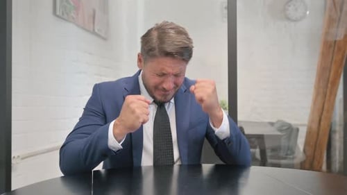 Frustrated Man in Suit Expressing Defeat in Office