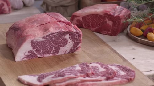 Raw Beef Ribeye Roasts and Slices on Butcher Block