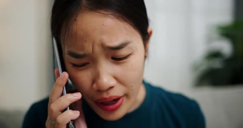 Worried Young Woman Talking on Phone Indoors