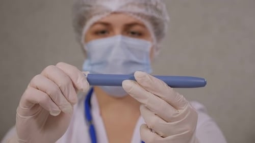 Ein Arzt hält einen Insulinstift in der Hand, während er in einem Krankenhaus an einem Tisch sitzt