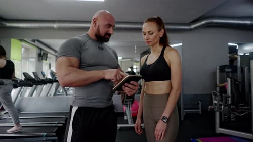 Trainer and Woman Discussing Fitness Goals in Gym