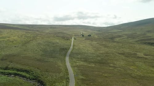 Winding road cutting through the rolling green hills of the Wicklow Mountains in Ireland