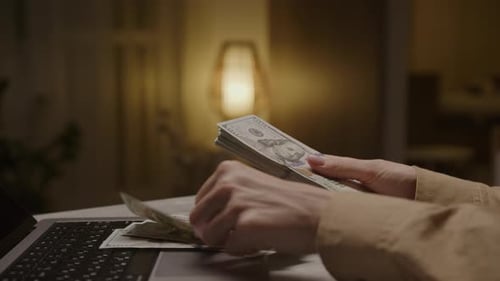 Hands Counting United States Currency With Laptop