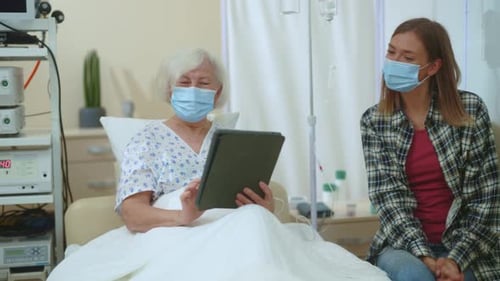 Senior Woman Using Tablet in Hospital With Young Woman