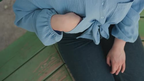 Woman Retrieves Earbuds from Case on Park Bench