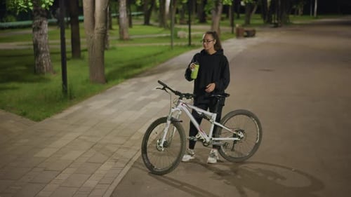 Woman Examines Phone On Bike Path Female Pauses To Check Her Mobile By Bicycle Woman Stops Beside