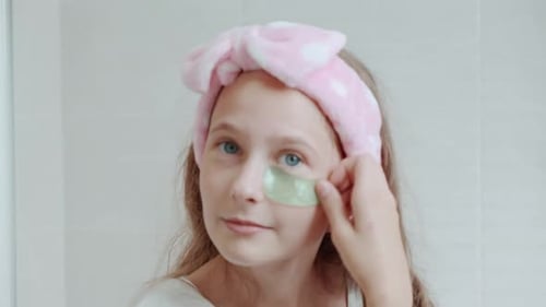 Girl Applies Cosmetic Eye Patches in Bathroom