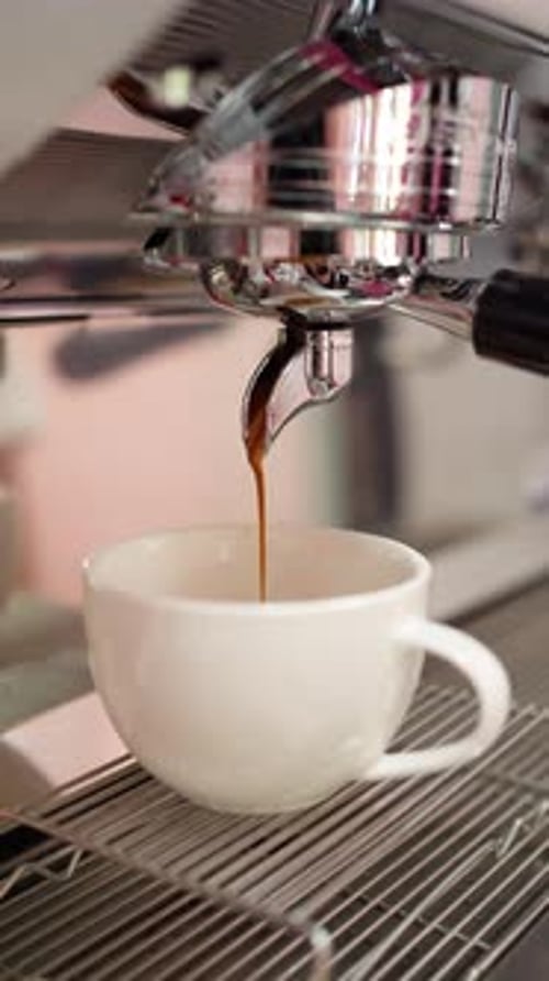 Espresso machine pouring coffee into a white mug