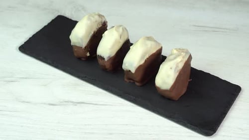 Hand puts chocolate dessert on dish for serving. The chocolate chip cookie is placed on black
