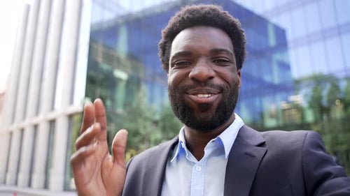 Smiling Man Waving in Front of Office Building