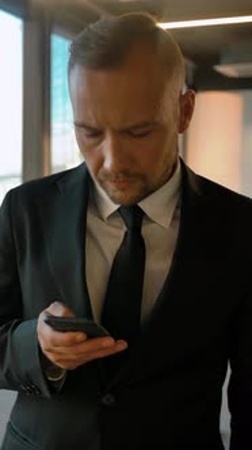 Man In Suit Uses Smartphone Indoors