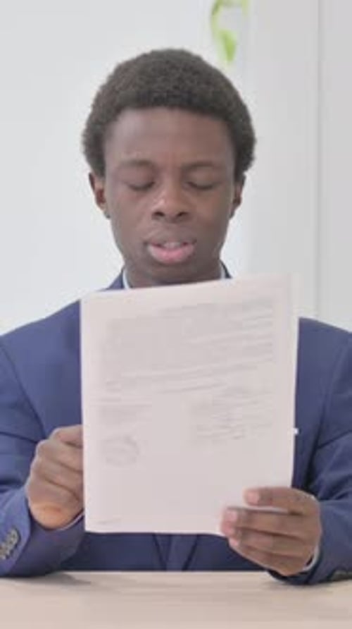 Man Reads a Document, Visibly Upset by the Contents
