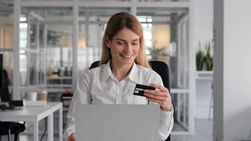 Empresária feliz usando laptop e cartão de crédito para fazer compras