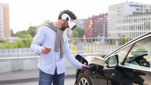 Man Charging Electric Car with VR Headset