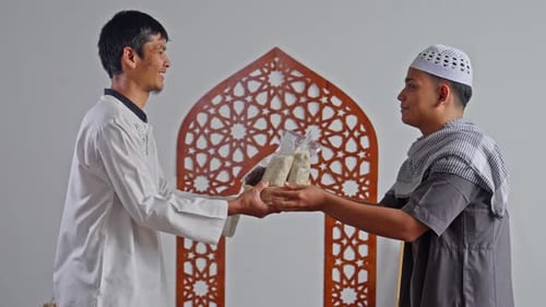 Muslim man with respect giving Zakat Al-Fitr rice to brother in need at mosque