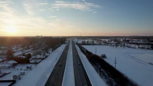 Drone view of beautiful snowy highway in the evening sunset.