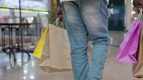 Man with Shopping Bags Walks Through Indoor Mall