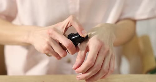 Woman squeezing foundation onto hand indoors, closeup. Camera moving forward