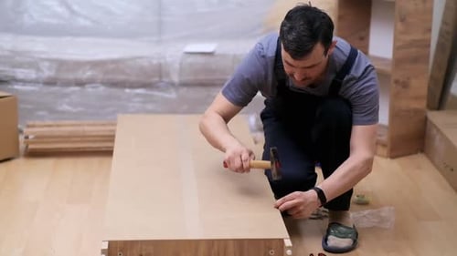 Man Hammers Wood Plank