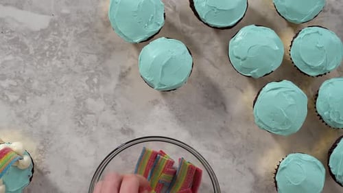 Flat Lay Decorating Chocolate Cupcakes with Buttercream Frosting and Rainbow Candy